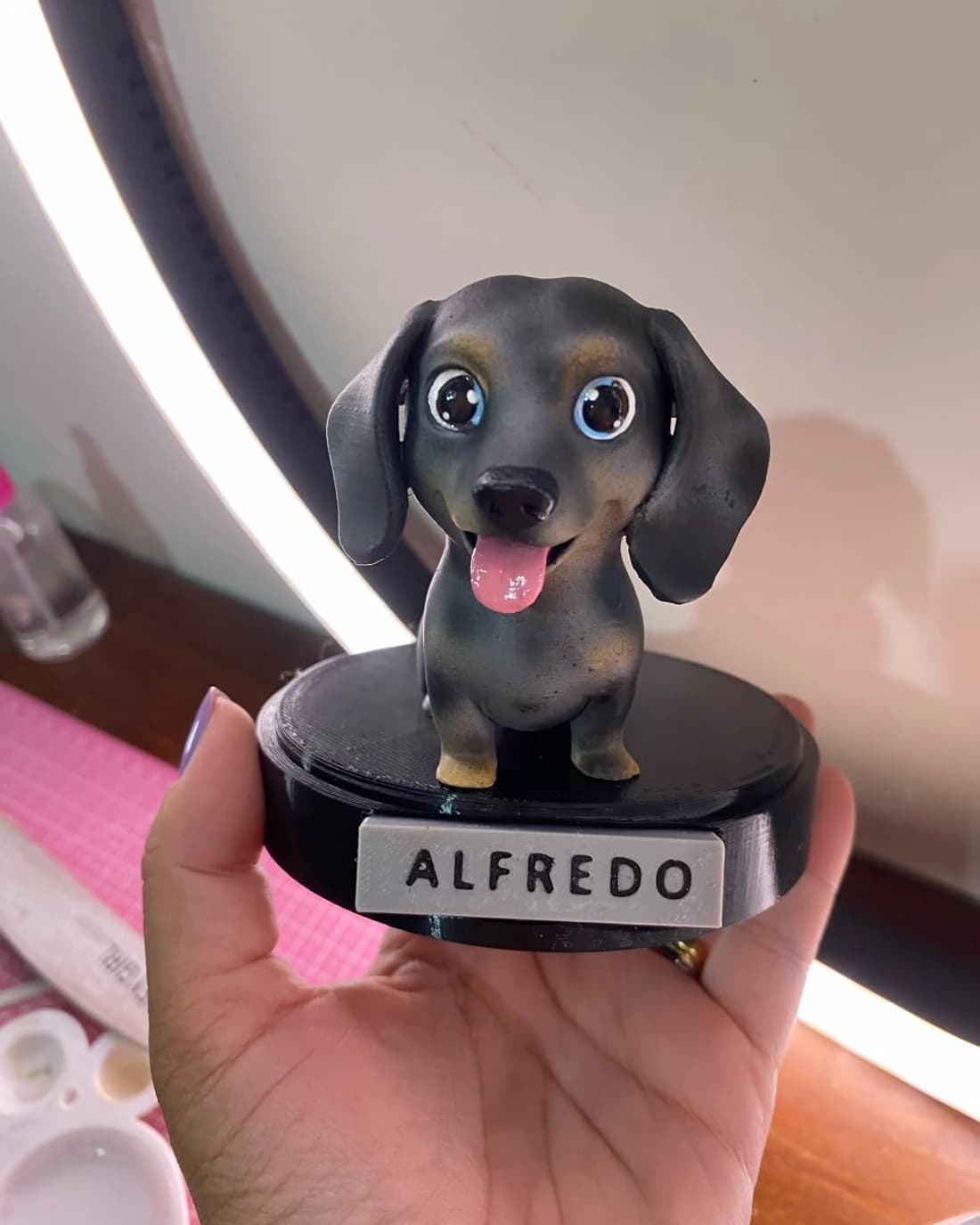 A peça de 12,5 cm da shih tzu Luna sobre fundo claro de estúdio, com a plaquinha gravada na base